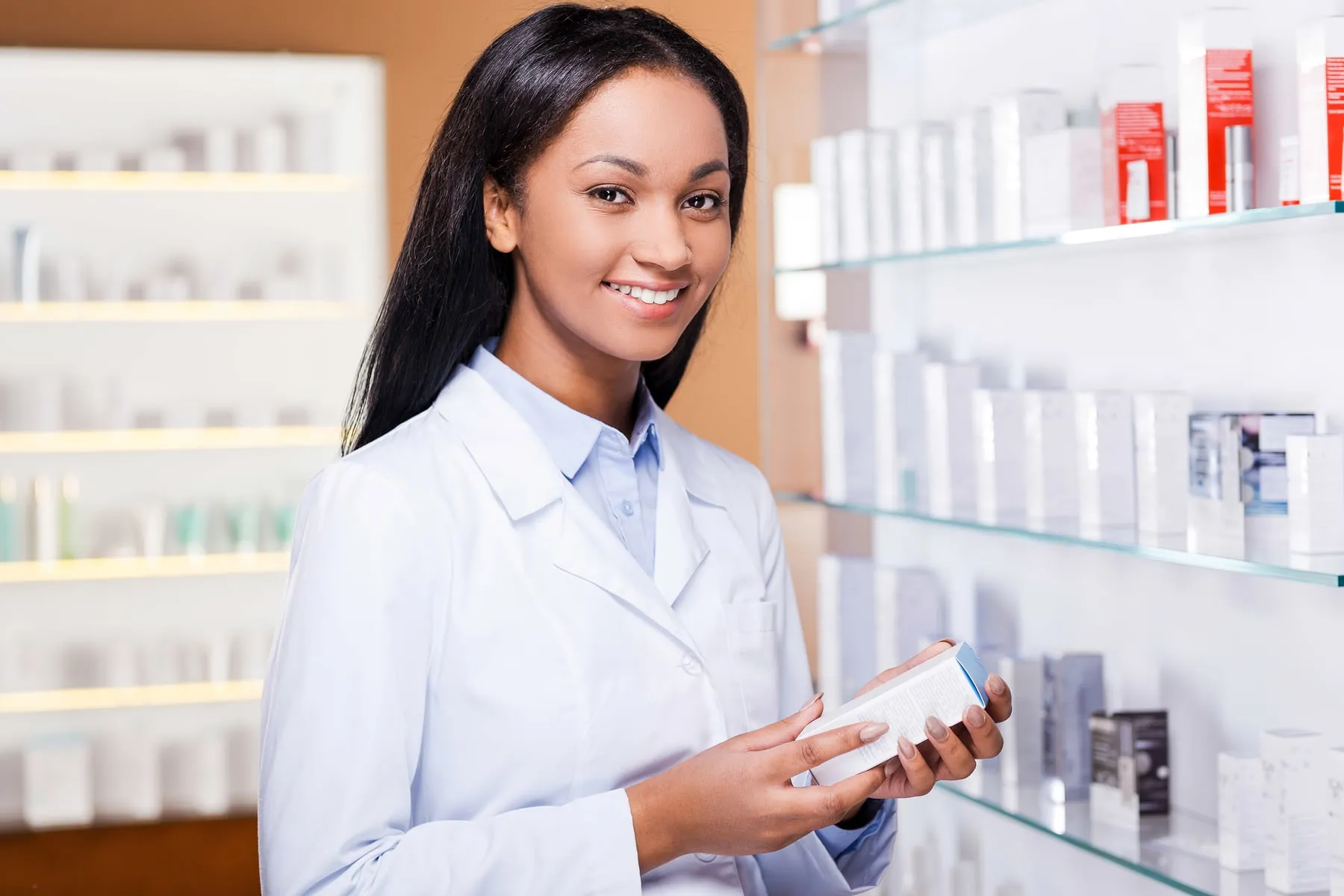 Professional in a lab coat holding a product in front of shelves