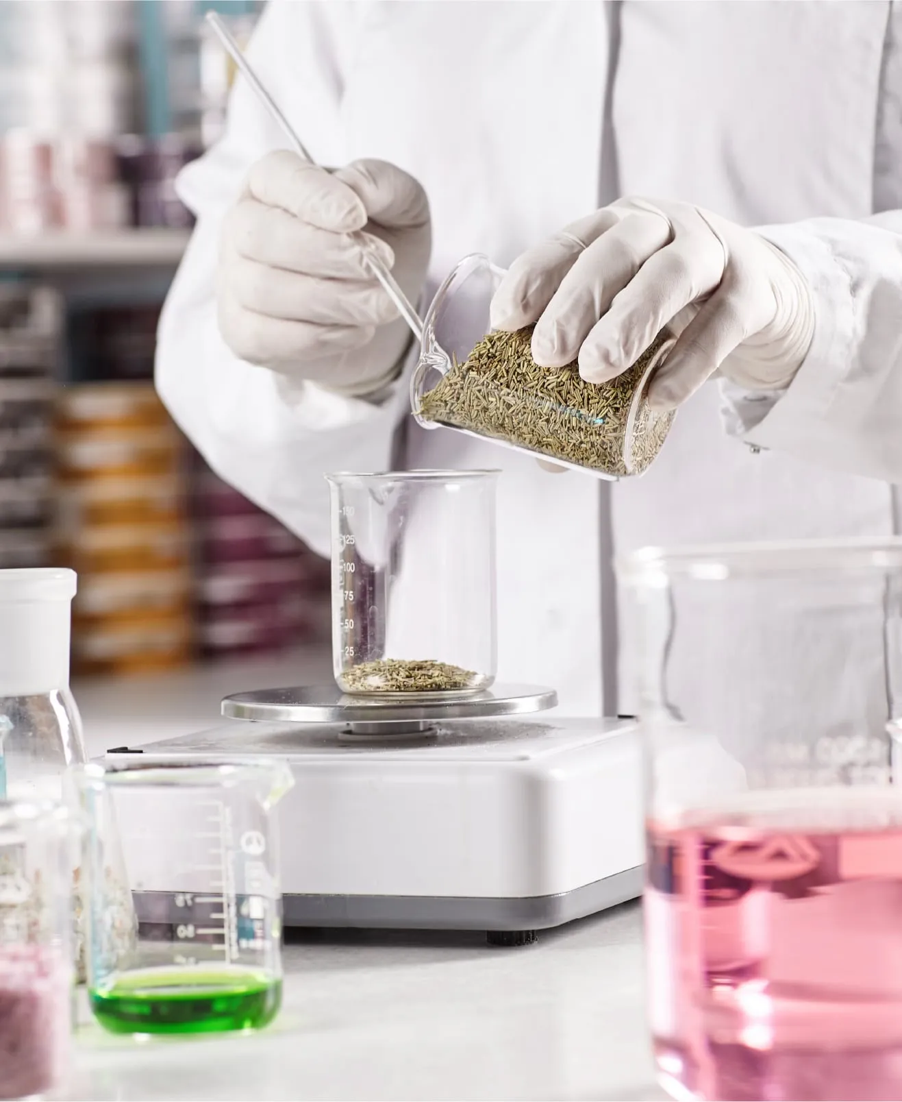 Weighing ingredients on a laboratory scale beside coloured solutions