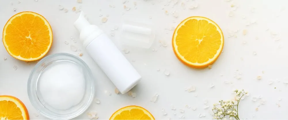 White serum bottle among orange slices